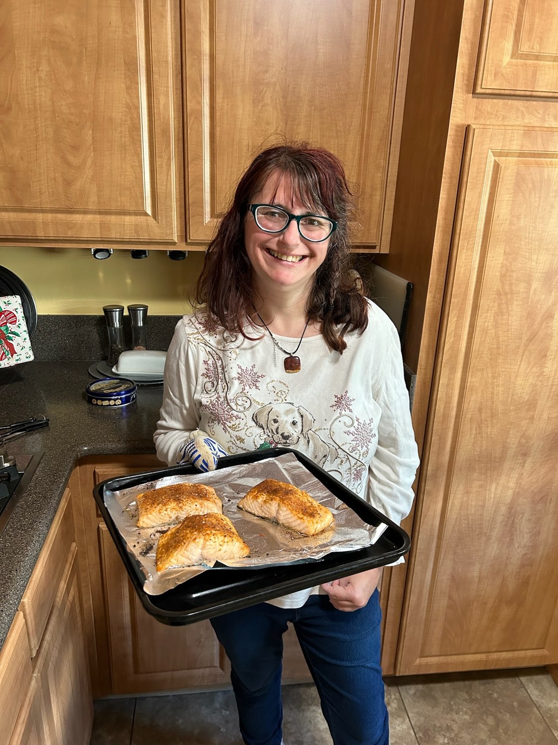A person in a kitchen holding a tray of baked food