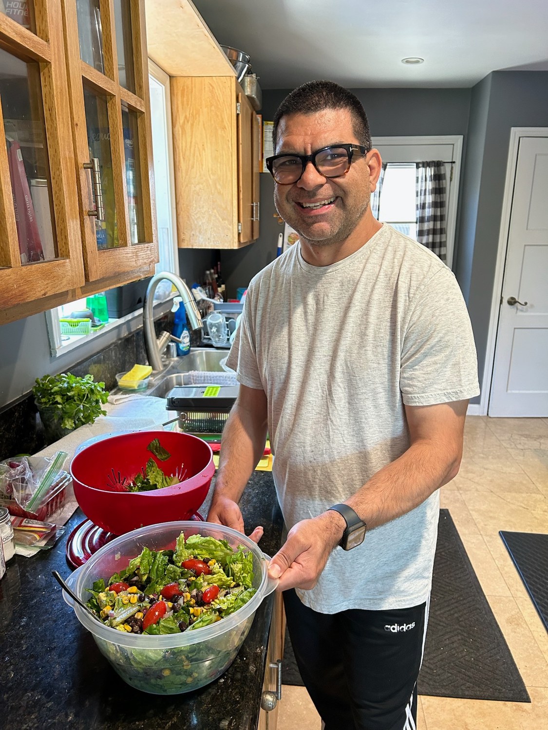 A person in a kitchen holding a bowl of salad