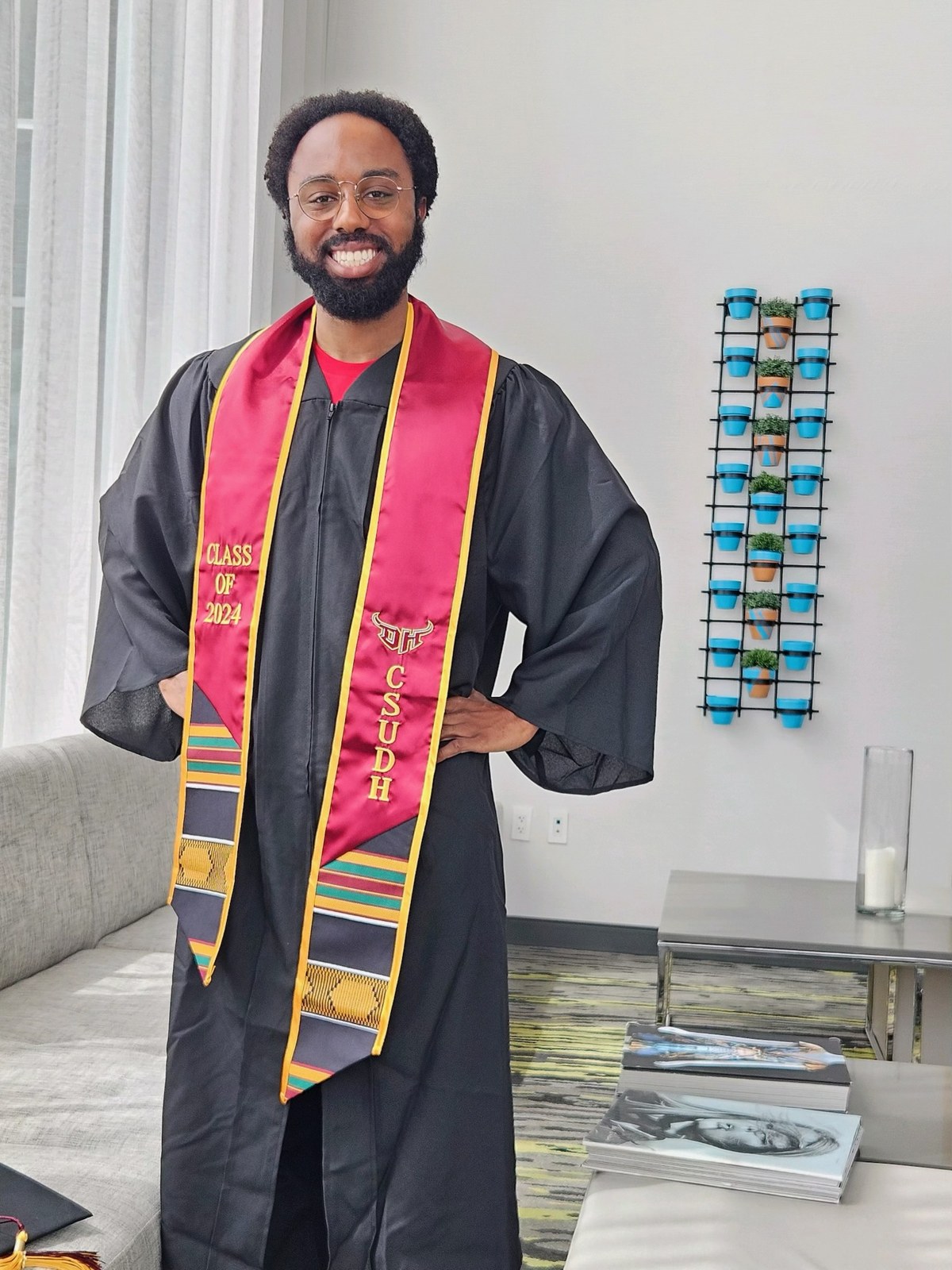 A person wearing a gown and red graduation stole.