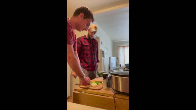 A still image of two people preparing food in a kitchen.