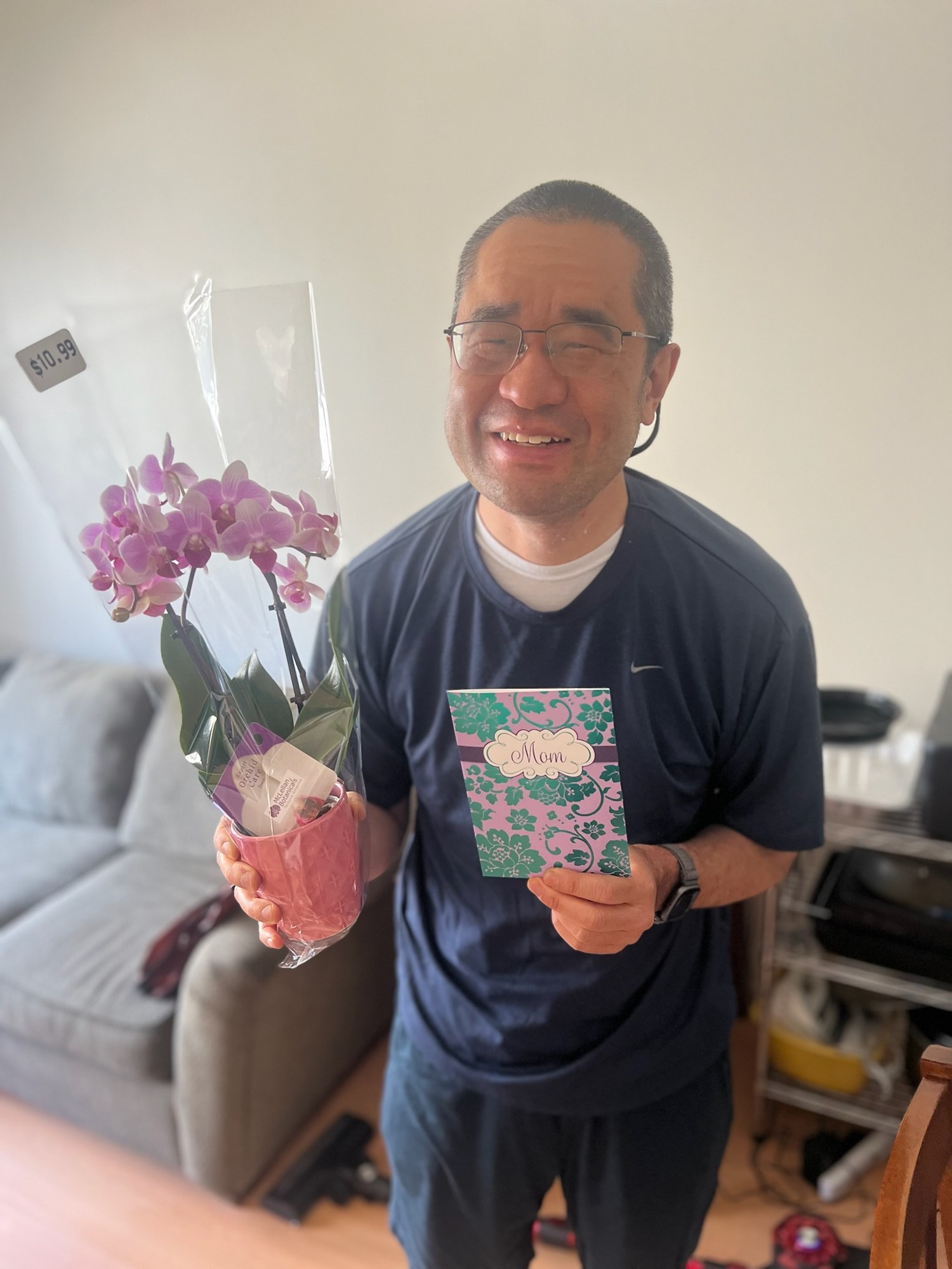 A person holding a purple orchid and a card labeled Mom.